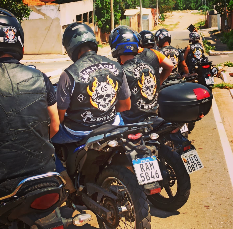 Homem de costas na moto usando colete com o brasão Irmãos de Estrada